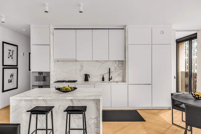 kitchen featuring white cabinets, stainless steel oven, backsplash, and modern cabinets