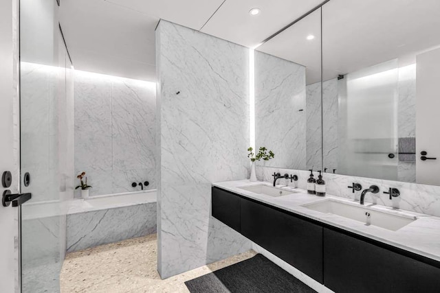 full bathroom featuring stone wall, a sink, and tile walls