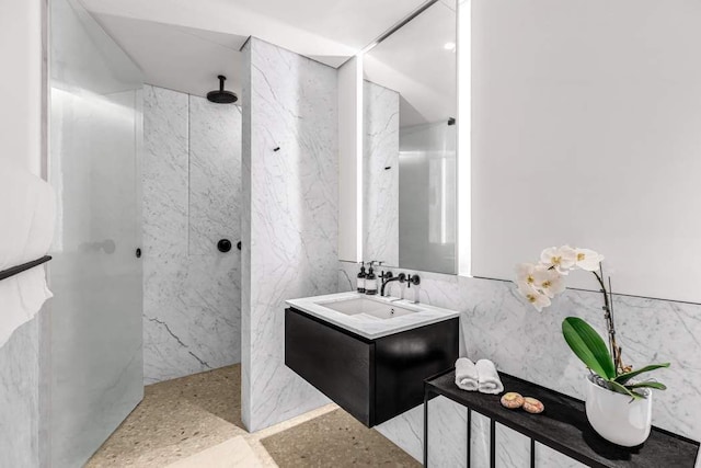 bathroom featuring tile walls, vanity, and a marble finish shower