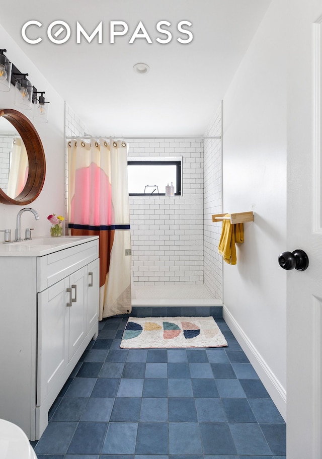 full bathroom with tiled shower, vanity, and baseboards