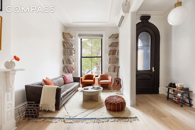 sitting room with a wall mounted AC, wood finished floors, and ornamental molding