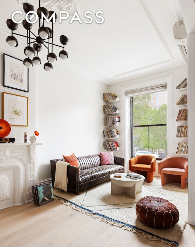 living room with an inviting chandelier, crown molding, wood finished floors, and a raised ceiling