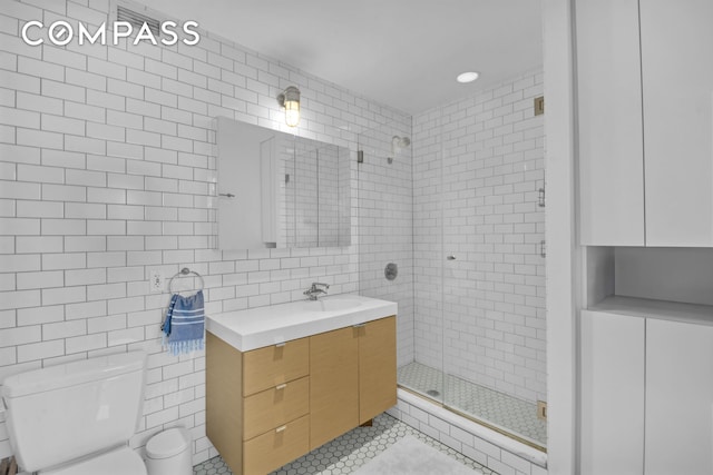 full bath with tile walls, toilet, a shower stall, vanity, and tile patterned floors