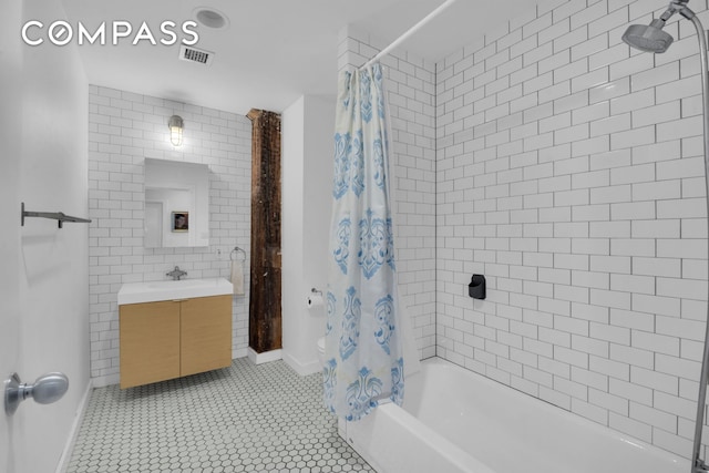 bathroom with shower / bath combo, visible vents, tile patterned flooring, vanity, and tile walls