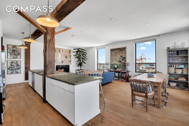 kitchen featuring dark countertops, light wood finished floors, white cabinetry, and a healthy amount of sunlight