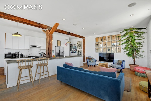 living area with beamed ceiling, wood finished floors, and recessed lighting