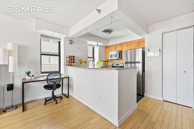 kitchen featuring baseboards, a peninsula, stainless steel appliances, a textured ceiling, and light wood-style floors