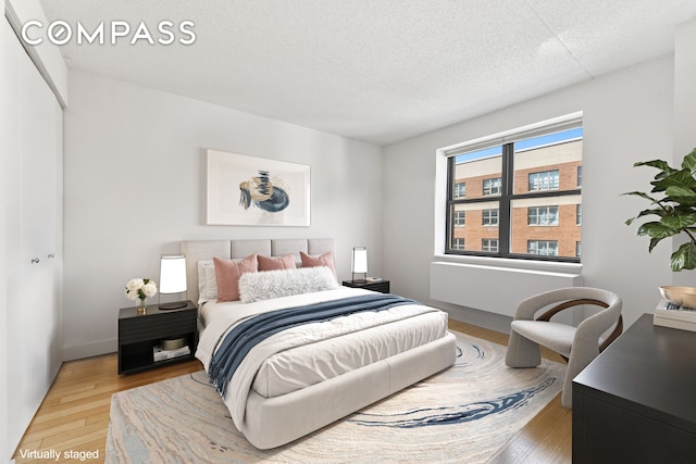 bedroom with light wood-style floors and a textured ceiling