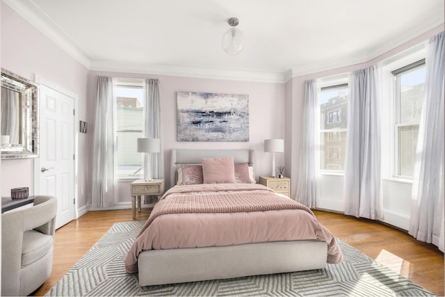 bedroom with multiple windows, light wood-type flooring, baseboards, and ornamental molding