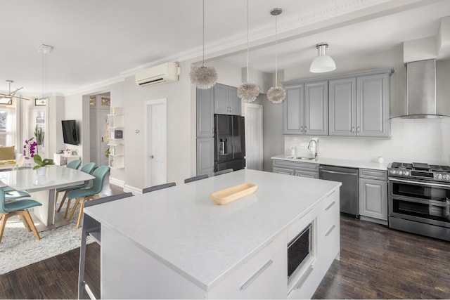 kitchen with a wall mounted air conditioner, gray cabinets, appliances with stainless steel finishes, and a sink