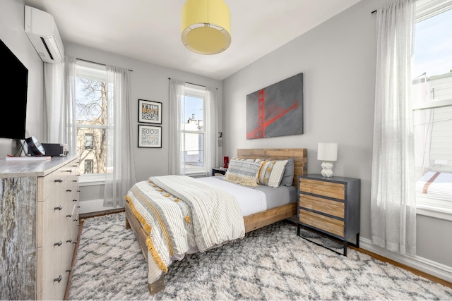 bedroom with baseboards and a wall unit AC