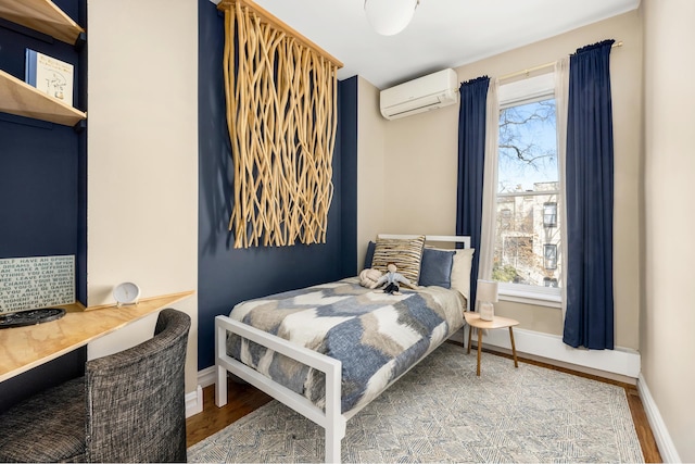 bedroom featuring an AC wall unit, wood finished floors, baseboards, and built in study area