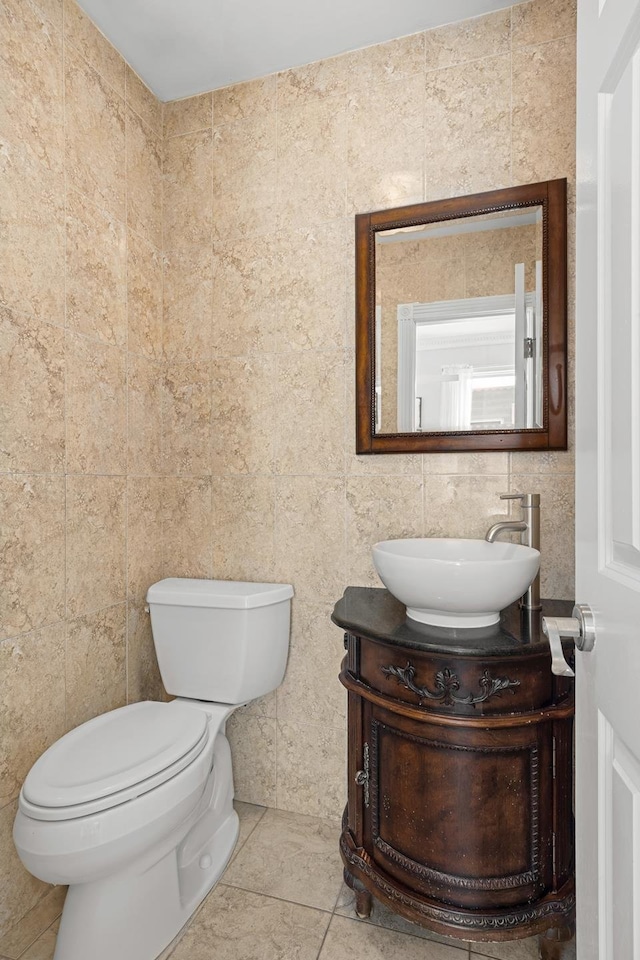 half bath featuring tile patterned floors, toilet, and vanity