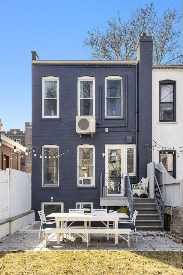 rear view of house with ac unit, fence, brick siding, a chimney, and a patio area