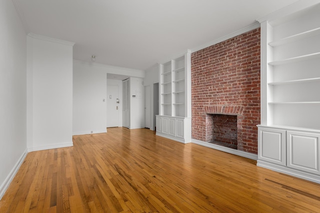 unfurnished living room with baseboards, built in shelves, a brick fireplace, and light wood-style flooring