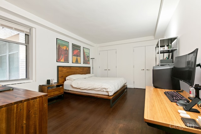 bedroom featuring dark wood-style floors and two closets