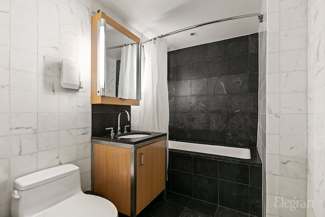 full bath featuring tiled shower / bath, toilet, vanity, and tile walls