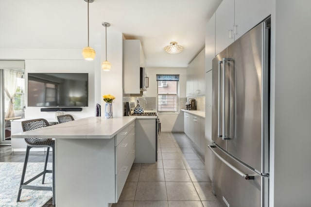 kitchen with premium appliances, a breakfast bar area, tasteful backsplash, light countertops, and a peninsula