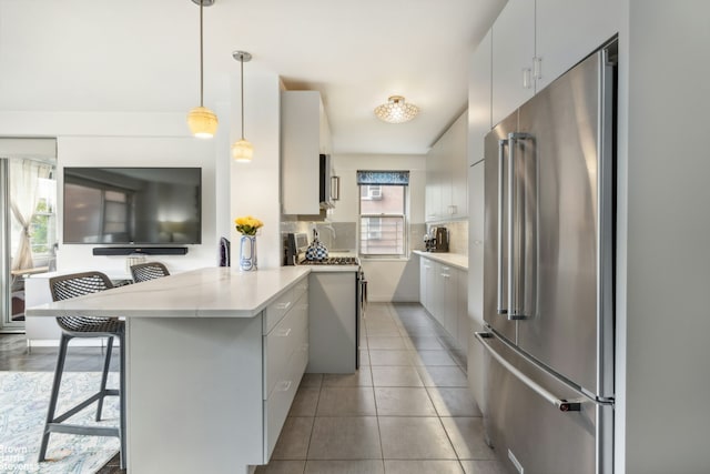 kitchen with a kitchen breakfast bar, light countertops, high quality appliances, a peninsula, and backsplash