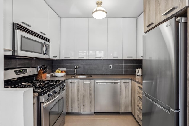 kitchen with appliances with stainless steel finishes, a sink, and modern cabinets