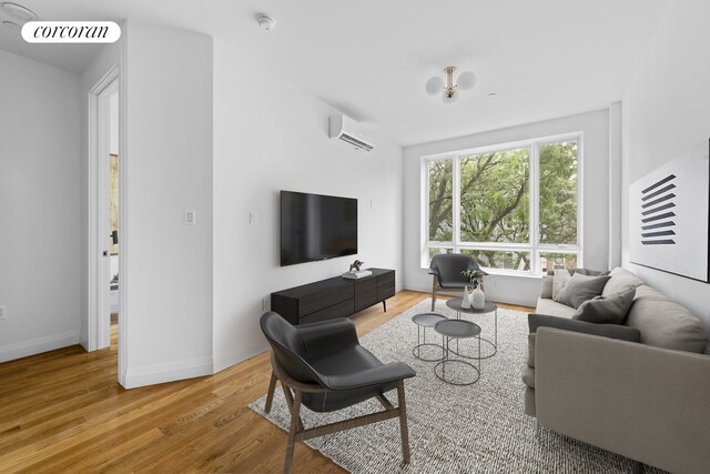 26 Goodwin Pl Unit 3F, New York City, NY 11221 - living room featuring visible vents, an AC wall unit, baseboards, and wood finished floors