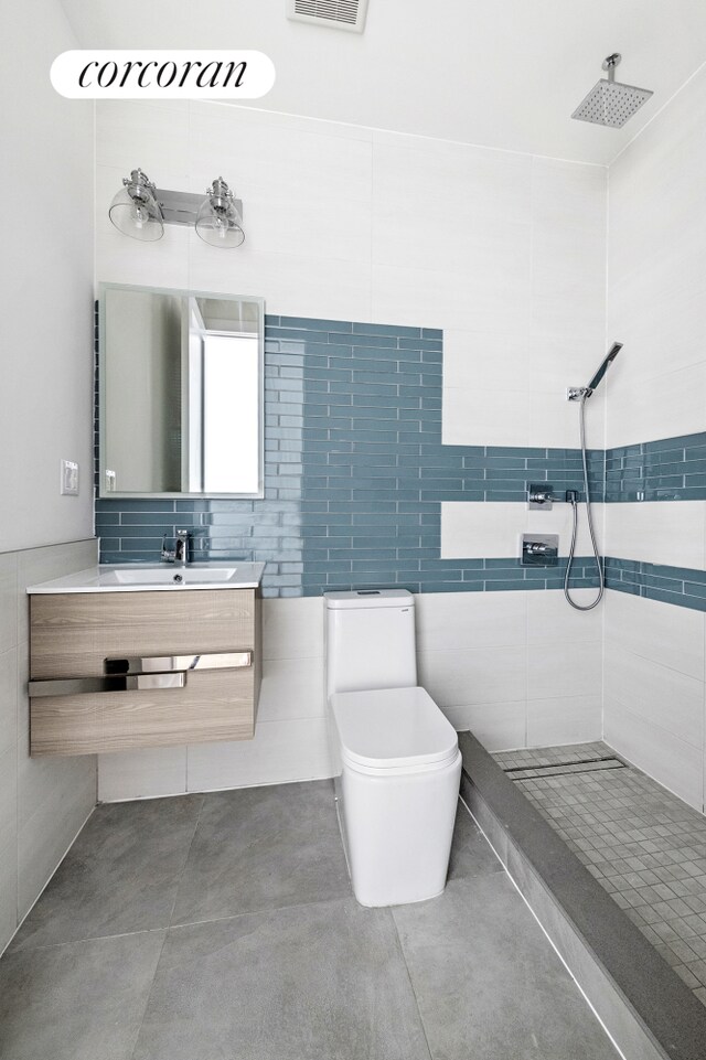 26 Goodwin Pl Unit 3F, New York City, NY 11221 - full bathroom featuring visible vents, a tile shower, tile walls, toilet, and vanity
