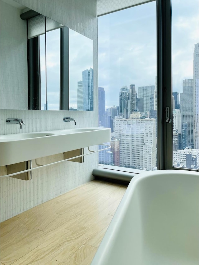 full bathroom featuring a view of city, a soaking tub, and wood finished floors