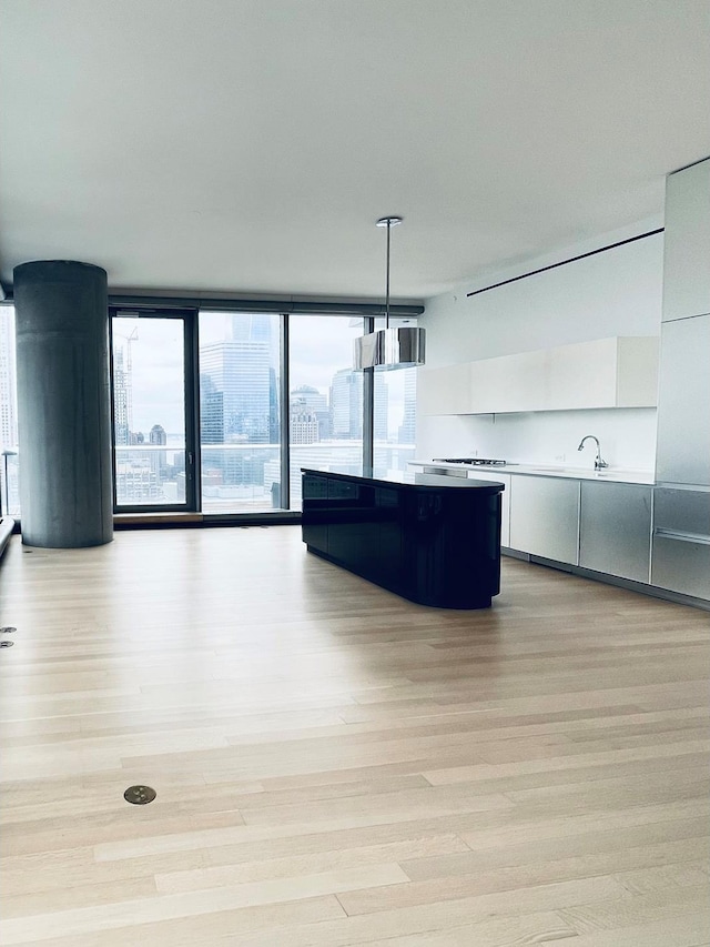 kitchen with light wood-style floors, modern cabinets, white cabinetry, and a center island