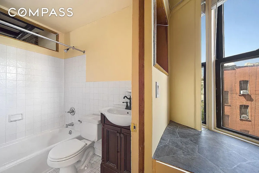 bathroom with vanity, toilet, tile walls, tile patterned floors, and shower / bath combination