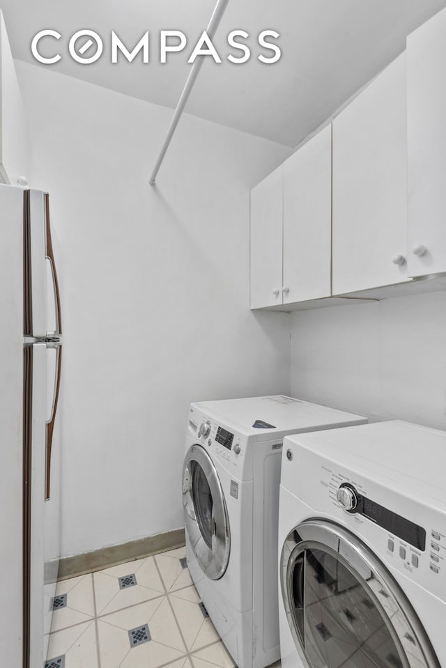 washroom featuring cabinet space, light tile patterned floors, baseboards, and independent washer and dryer