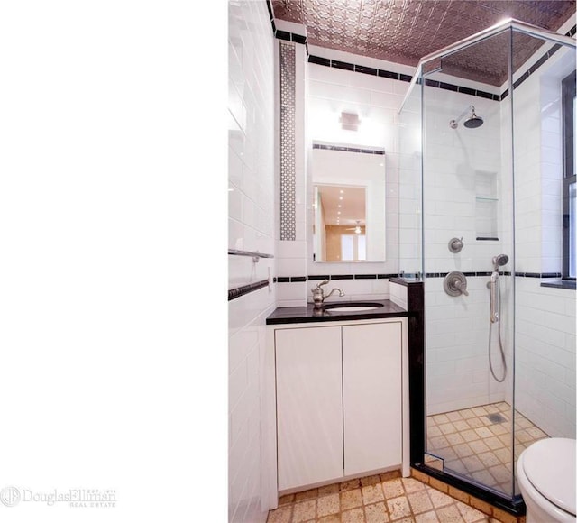 full bath with a stall shower, toilet, tile walls, and vanity