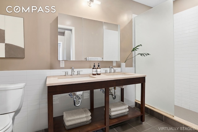 full bath with a sink, tile walls, toilet, and tile patterned floors