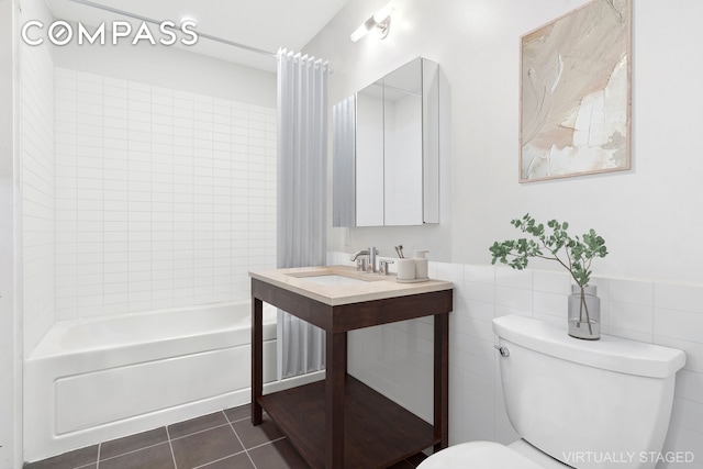 bathroom featuring tile walls, shower / bath combination with curtain, toilet, a sink, and tile patterned floors