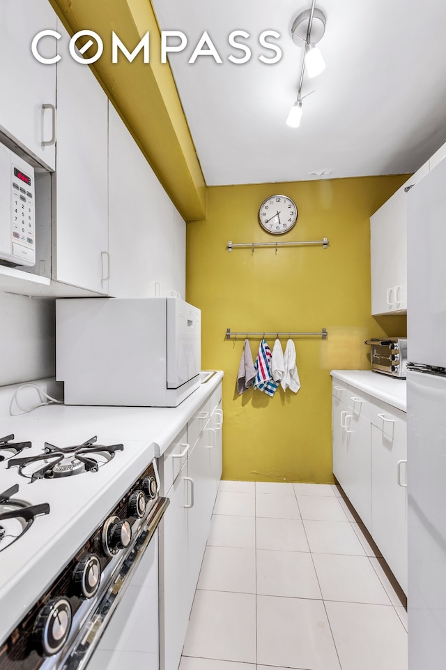 kitchen with white appliances, white cabinets, light tile patterned flooring, and light countertops