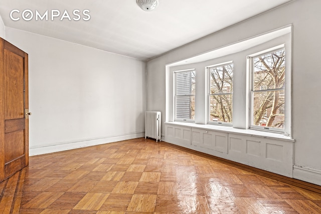 unfurnished room featuring radiator heating unit and baseboards