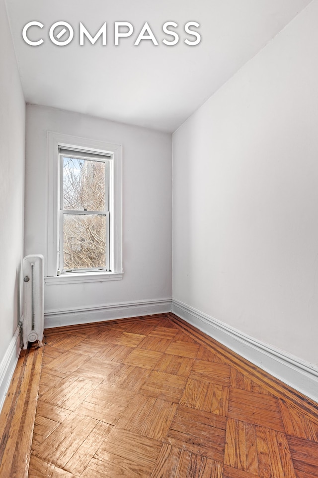 spare room with baseboards and radiator