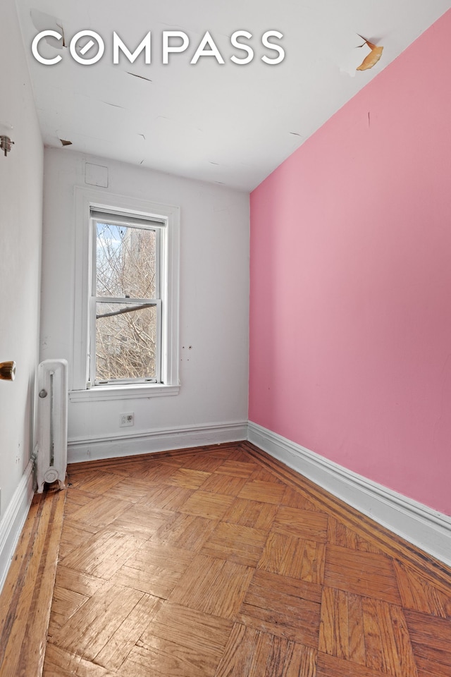 spare room with radiator and baseboards