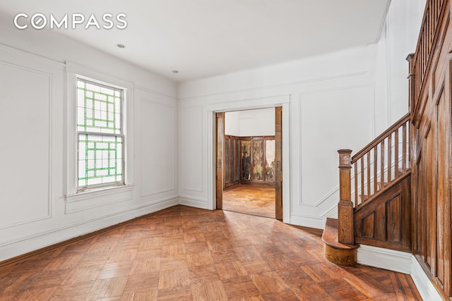 unfurnished room with a decorative wall and stairway