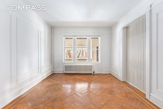 unfurnished room featuring a decorative wall and radiator heating unit