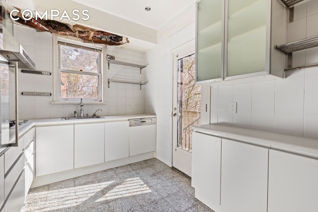 kitchen featuring light countertops, decorative backsplash, white dishwasher, granite finish floor, and a sink