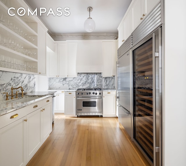 kitchen featuring custom range hood, high quality appliances, white cabinets, and a sink