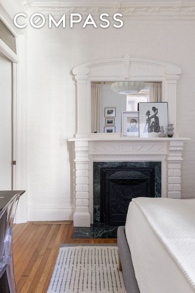 bedroom with hardwood / wood-style flooring, baseboards, and a high end fireplace