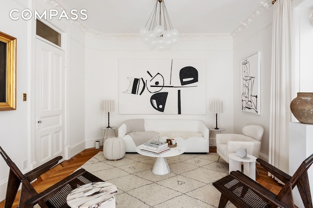 living area featuring ornamental molding, a chandelier, and baseboards