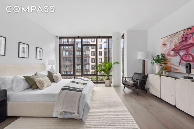 bedroom with a wall of windows and wood finished floors