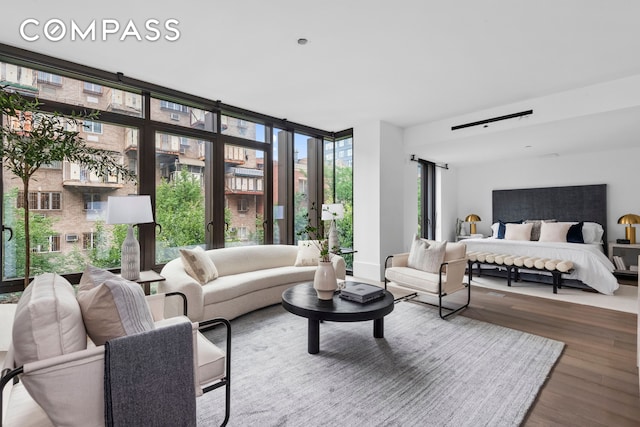 bedroom with a wall of windows and wood finished floors