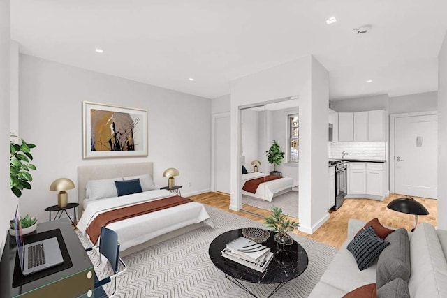 bedroom featuring light wood-style flooring, baseboards, a sink, and recessed lighting