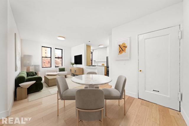 dining space featuring light wood-type flooring and baseboards