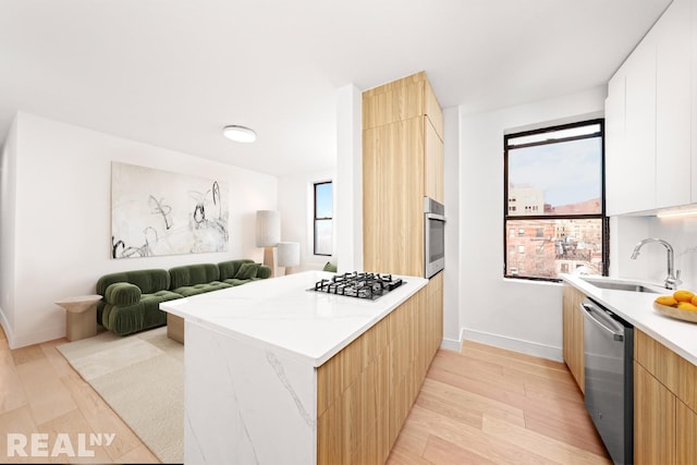 kitchen with a peninsula, a sink, appliances with stainless steel finishes, plenty of natural light, and modern cabinets