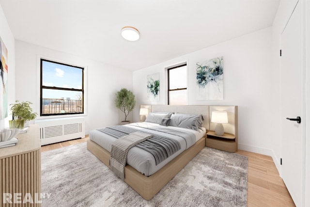 bedroom featuring baseboards, light wood-style floors, and radiator