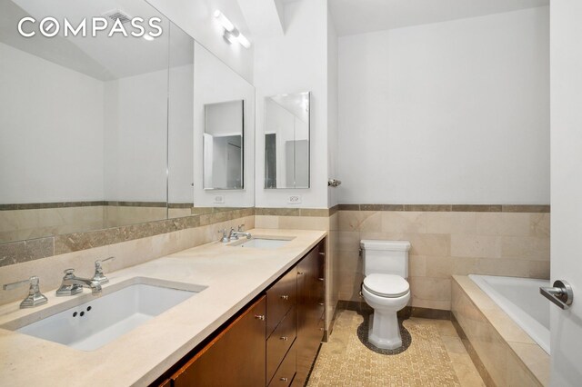 1 Hanson Pl Unit 15M, New York City, NY 11243 - bathroom featuring toilet, double vanity, tiled bath, tile patterned flooring, and wainscoting